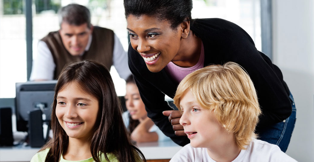Smiling teacher helping two children